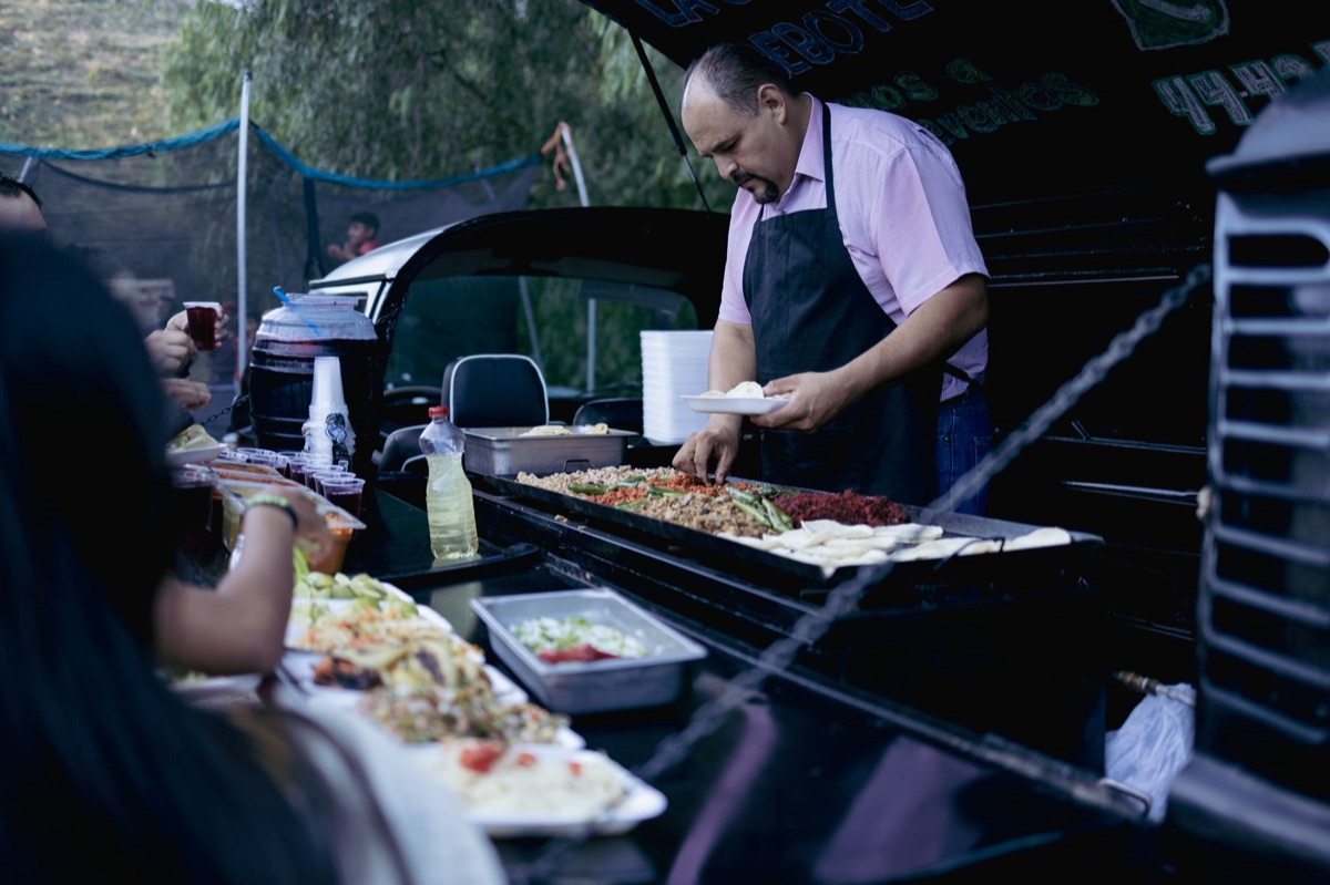 Taco truck window with steaming tacos and a 'I Love LA' sign