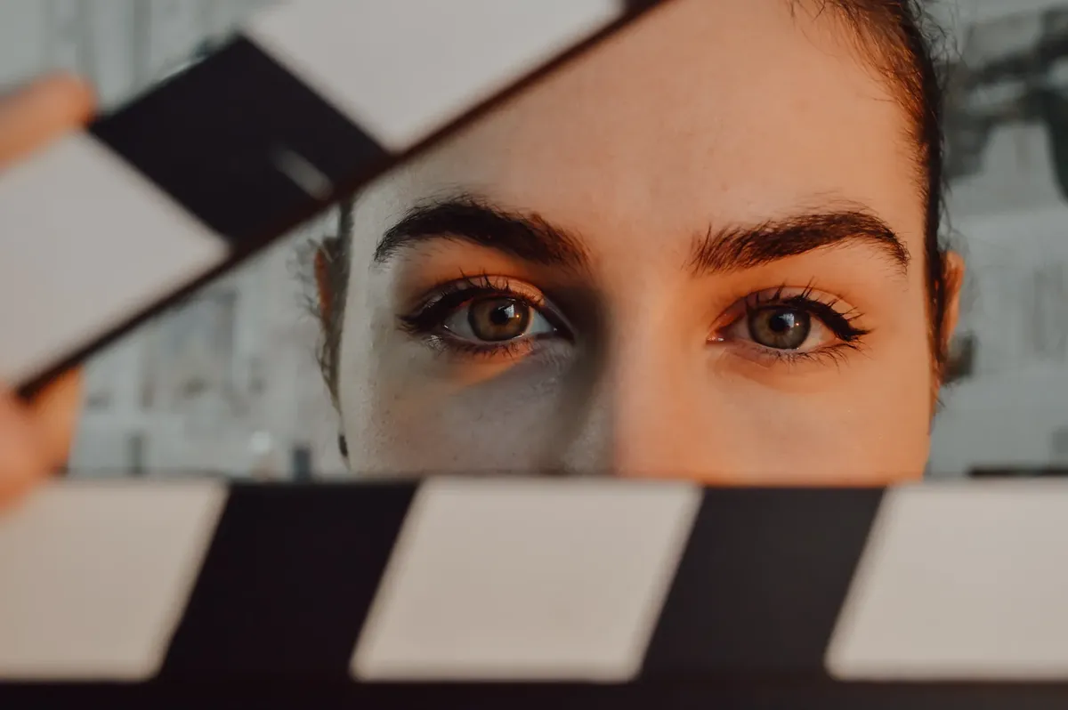 映画のクランプボードの後方にある人の目への迫力あるクローズアップ、映画制作の芸術性を象徴しています。