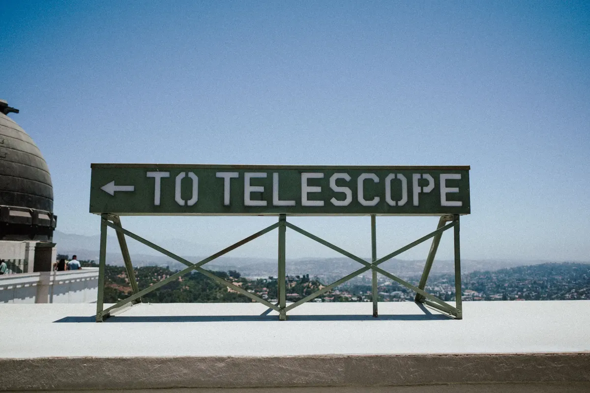 To Telescope sign at Griffith Observatory overlooking Los Angeles, CA skyline.