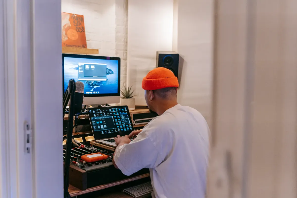 A music producer in a home studio using advanced technology to create music.